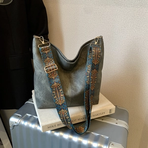 Deep grey tote bag with colorful bohemian wide strap on a stylish silver suitcase