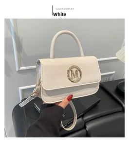 Détail du sac blanc à finition brillante avec boucle dorée en forme de lettre M
