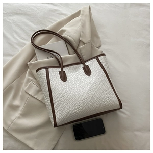 Dettaglio borsa tote crema goffrata coccodrillo con finiture in pelle marrone e manici