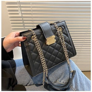 Close-up of black quilted shoulder bag featuring gold chain strap and metal lock detail