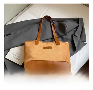 Detail of camel suede tote bag with brown leather base and fashion logo on suit