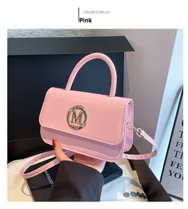 Détail d'un sac à main en cuir verni rose avec logo M doré et finition lisse