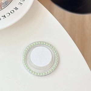 Close-up of light green pearl circular phone grip stand on a minimalist white table