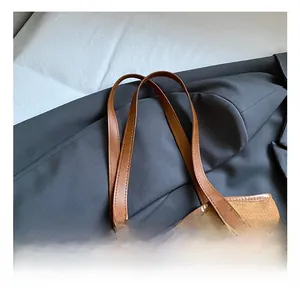 Close-up of brown suede tote bag with leather handles and Fashion embossed logo tag