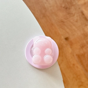 Detail of pink resin bear phone grip with magnetic base on a white surface