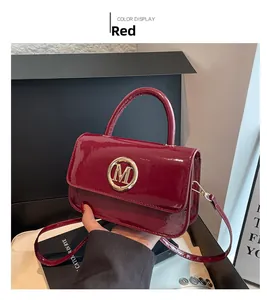 Détail du sac à main en cuir verni bordeaux avec finition brillante et boucle M en métal