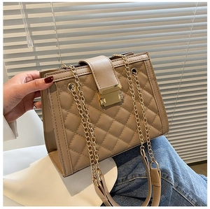 Close-up of beige quilted shoulder bag with golden chain strap and metal lock detail