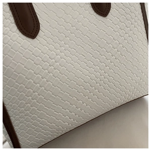 Macro della trama intrecciata bianca e del manico marrone scuro di una grande borsa tote