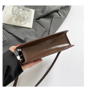 Vue détaillée du sac porté épaule en cuir verni marron foncé avec finition brillante et boucles