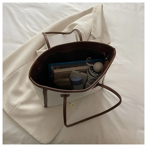 Dettaglio dell'interno della capiente borsa tote intrecciata beige con oggetti comuni