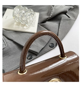 Détail d'un sac à main en cuir verni marron foncé avec anneau métallique doré élégant
