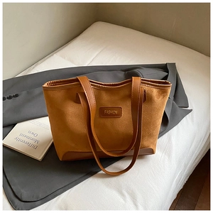 Detail of brown faux suede tote bag featuring reinforced corners and fashion brand tag