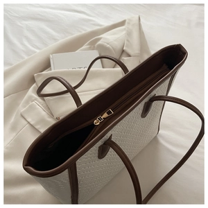 Dettaglio della borsa tote intrecciata bianca con bordi in pelle marrone e zip dorata