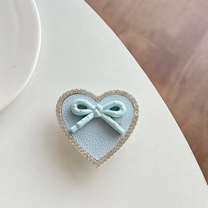 Close-up of heart-shaped blue leather phone grip with rhinestones and a bow