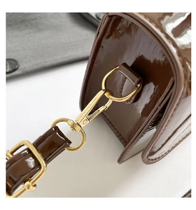 Détail d'un sac à main en cuir verni marron foncé avec attaches en métal doré poli