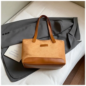 Detail of a brown patchwork tote bag with fashion tag on textured suede and smooth leather