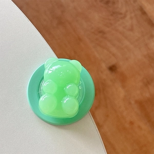 Detail view of a light green bear-shaped MagSafe phone grip with a semi-transparent finish