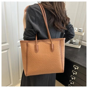 Dettaglio di una borsa tote marrone intrecciata con motivo a scacchi in pelle PU