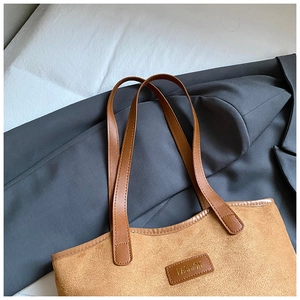 Close-up of suede tote bag with leather straps and Fashion embossed logo detail