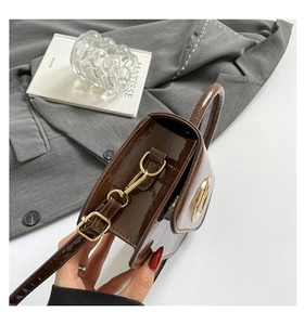 Détail d'un sac en cuir verni marron foncé avec anneaux dorés et profil structuré chic