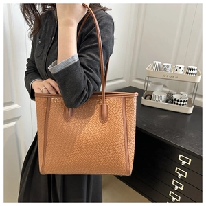 Dettaglio della borsa tote marrone intrecciata indossata da una modella in interni