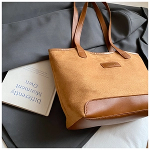 Detailed macro view of brown suede tote bag with leather straps and FASHION logo tag