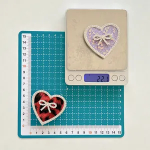 Detail view of heart-shaped rhinestone phone grips with bow accents on a measuring scale