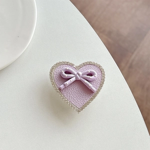 Close-up of heart-shaped rhinestone phone stand with purple leather and polka dot bow