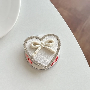 Macro view of heart-shaped rhinestone phone grip with leather texture and bow detail