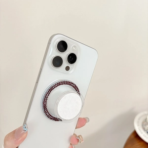 Close-up of a circular phone socket with deep red rhinestones on a white smartphone