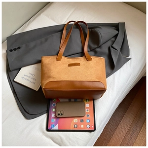 Top view of a brown patchwork tote bag with suede texture and commuter accessories