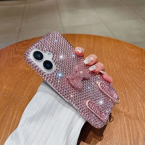 Detailed view of pink sparkling diamond bow phone case with hand straps for iPhone