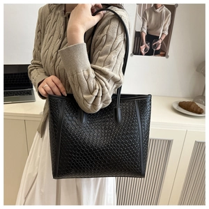 Vista dettagliata della trama intrecciata della borsa tote in pelle nera e manici