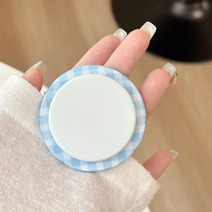 Close-up of blue and white checkered magnetic phone socket stand held in hand