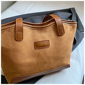 Close-up of caramel suede tote bag featuring a leather patch with gold FASHION lettering