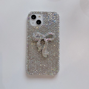 Macro shot of luxury iPhone case with dense rhinestones and 3D bow on light background