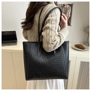 Modella che indossa una borsa tote in pelle intrecciata nera in una stanza minimalista