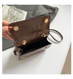 Détail du sac en cuir verni marron foncé montrant le fermoir magnétique doré et la doublure