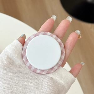 Close-up of pink gingham pattern round magnetic phone grip held by a hand