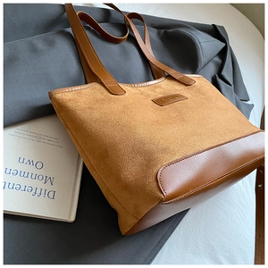 Detailed shot of brown patchwork tote bag with fashion tag on textured suede and leather