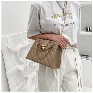 Quilted khaki crossbody bag with gold chain strap worn by model in a minimalist setting