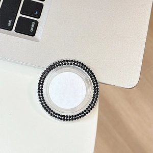 Close-up of black rhinestone phone grip holder on a sleek silver laptop surface