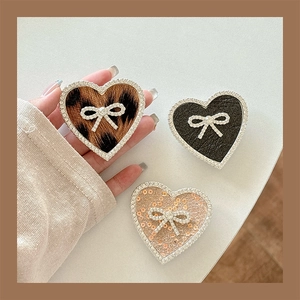 Detail of heart phone grips with leopard print, leather texture and pink sequins with bows