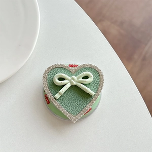 Macro detail of heart-shaped phone grip with green leather texture and rhinestone edge