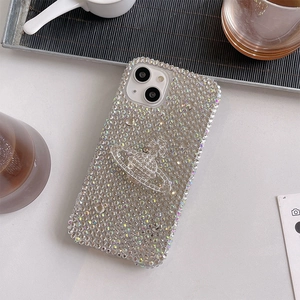 Detail of luxury rhinestone phone case with Saturn logo for iPhone on coffee table