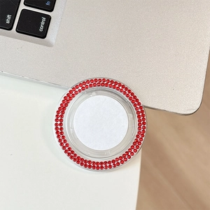 Detail of a phone grip with two rows of red rhinestones and a white center on a desk