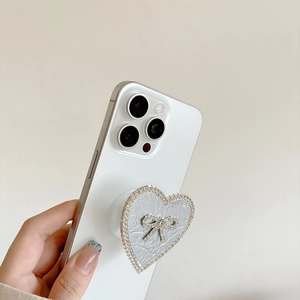 Silver metallic heart phone socket with rhinestone bow detail on a white smartphone