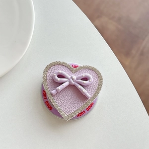 Detail view of heart-shaped phone grip with purple leather, bow, and rhinestone trim