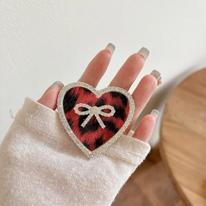 Close-up of leopard heart phone grip with sparkling rhinestone bow and crystal edge