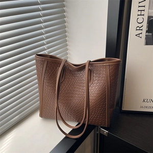 Borsa tote marrone a trama intrecciata con spalline sottili su sfondo moderno